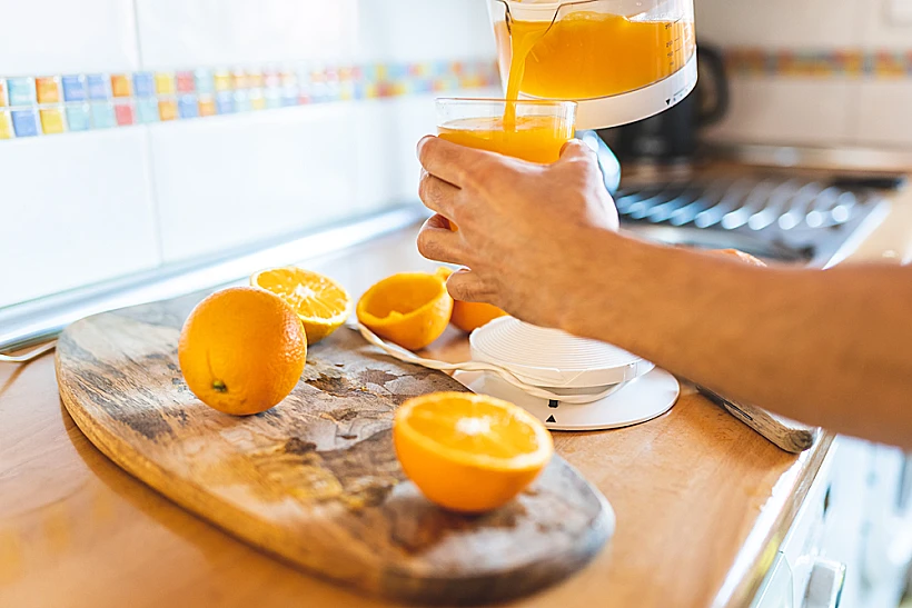 Close,of,man,squeezing,oranges,using,electric,squeezer.,person,preparing
