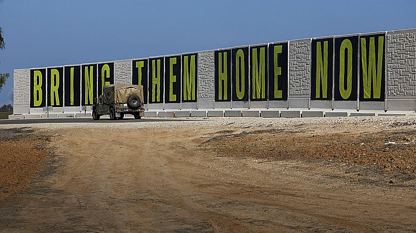 ג'יפ צבאי סמוך לרצועת עזה, על רקע כרזה הקוראת לשחרור החטופים