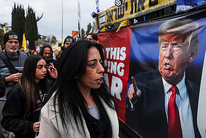 עינב צנגאוקר בהפגנת משפחות חטופים, כשמאחוריה שלט עם תמונתו של הנשיא טראמפ