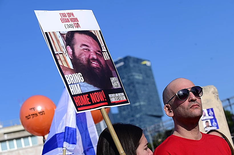 יאיר הורן עם תמונת אחיו איתן בכיכר החטופים