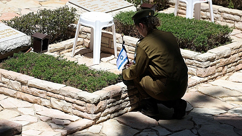 חיילת מניחה את דגל הלאום על קבר חלל בהר הרצל