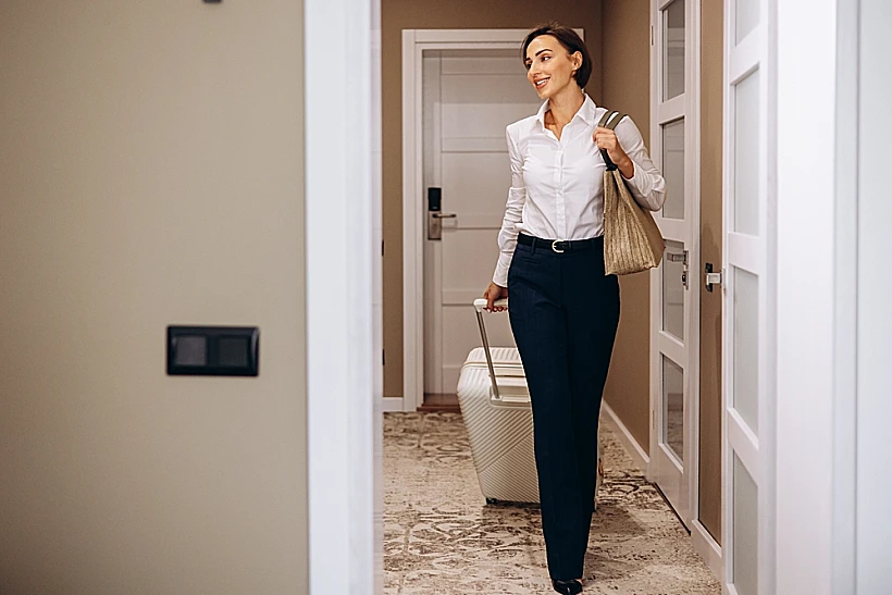 אישה עם טרולי במסדרון של בית מלון נכנסת לחדרluggage