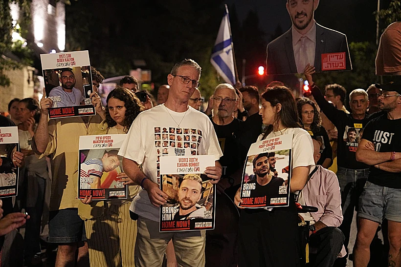 אוהד בן עמי ובנותיו עם תמונותיהם של החטופים שהוחזקו עמו בשבי