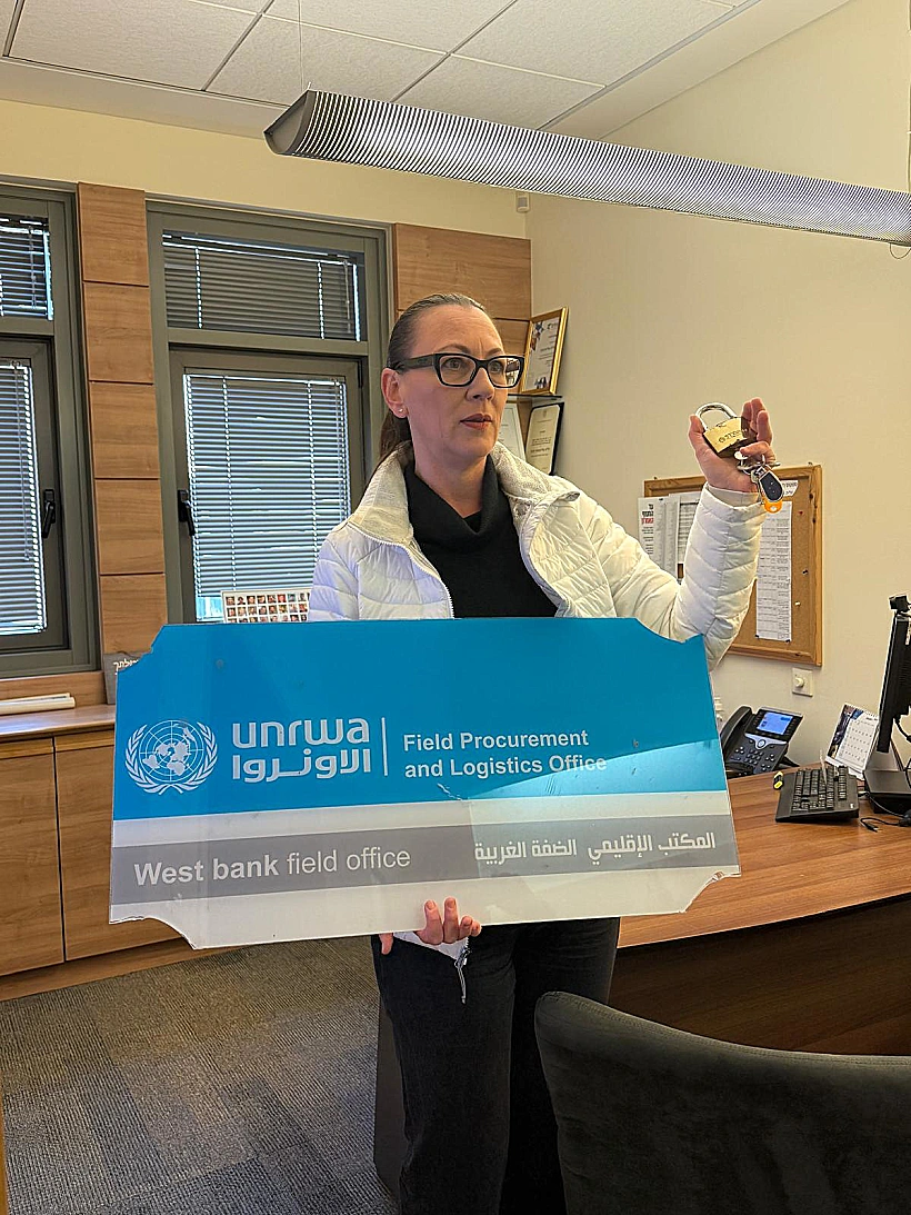 ח"כ יוליה מלינובסקי עם שלט ממטה אונר"א בירושלים