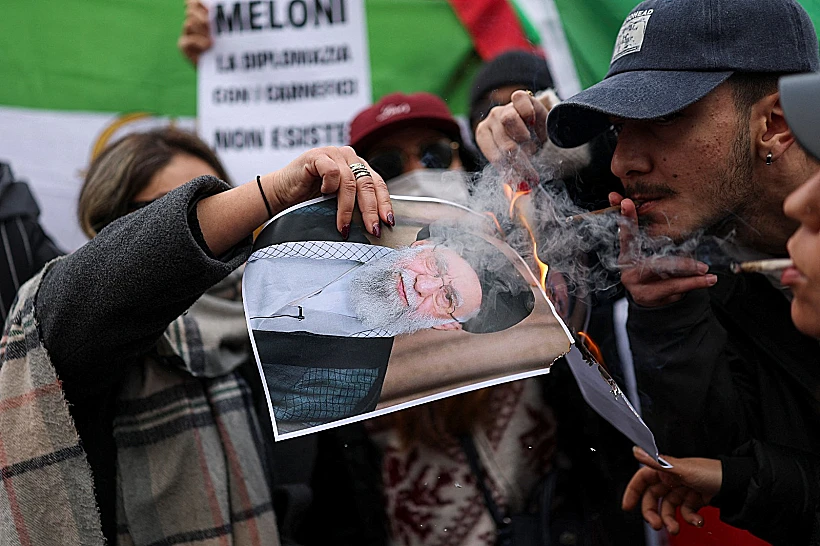 מציתים סיגריות מתמונה בוערת של חמינאי, בעצרת מול הקונסוליה האיראנית במילאנו