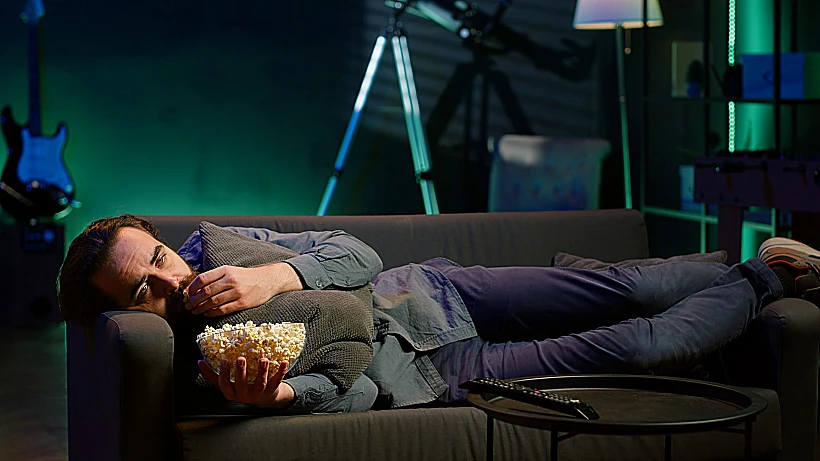 גבר אוכל פופקורן מול הטלוויזיה