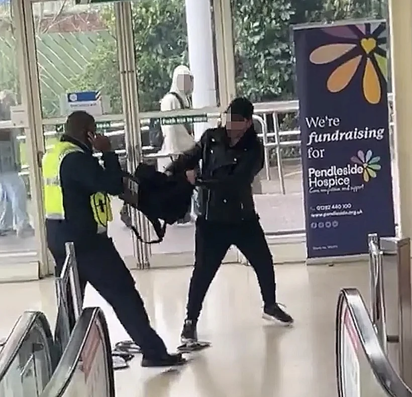 המאבטח אוחז בתיק בעוד החשוד מנסה להשתחרר