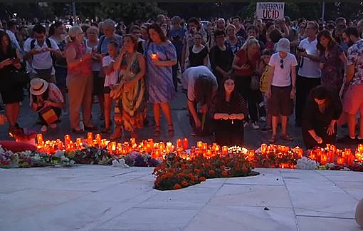 אנשים מדליקים נרות מול מרכז המטה הממשלתי בבוקרשט בעקבות רצח הנערה בת ה-15
