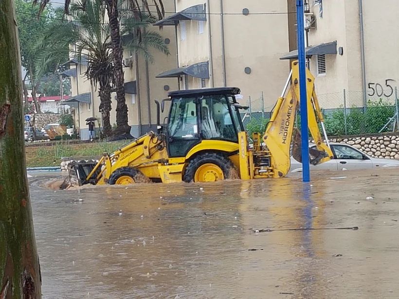 טרקטור מפלס את דרכו בהצפה בשדרות