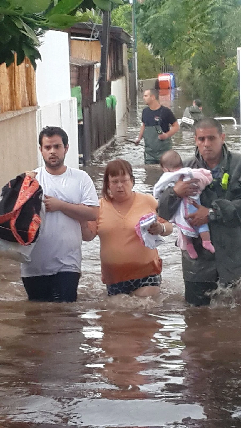 לוחמי האש מסייעים לאזרחים להיחלץ מהשטפונות.