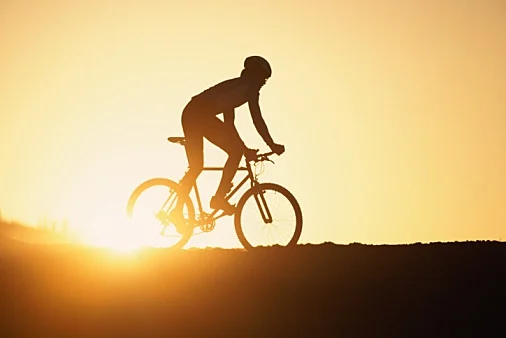 גבר רוכב על אופניים וברקע השקיעה