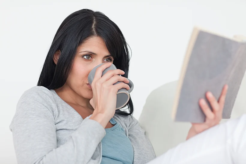 אישה קוראת ספר על הספה