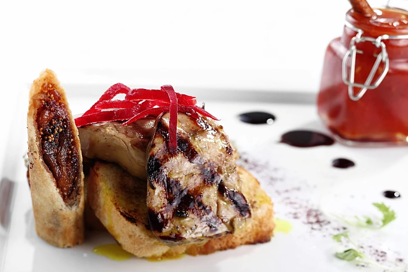 כבד אווז מונח על לחם בריוש לצד ריבת שרי מסעדת