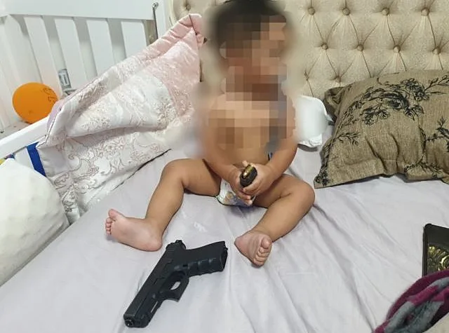 תיעד את בנו בן השנה וחמישה חודשים משחק בנשק ובמחסנית עם כדורים