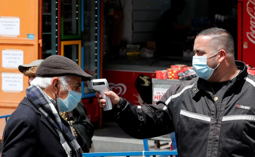 בעל חנות במחנה יהודה בירושלים בודק חום ללקוח