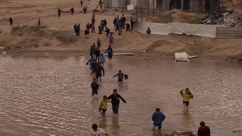 ילדים בכפר בדואי הולכים במים לאחר שהגשם הציף את השביל המוביל לבית הספר שלהם