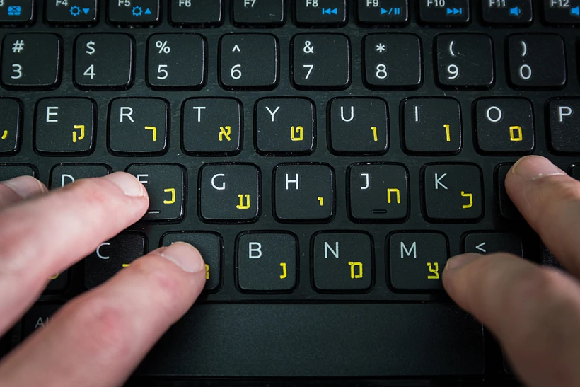 איש מקליד על מקלדת עם אותיות בעברית