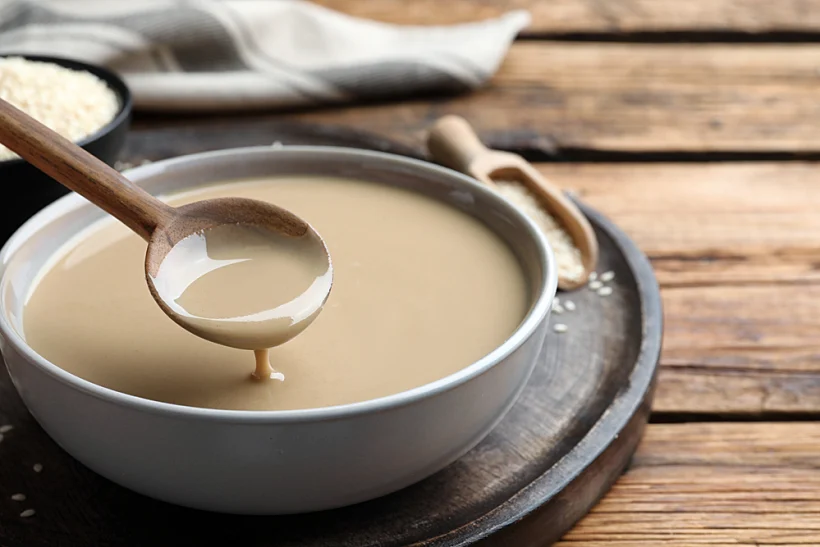 Spoon,with,tasty,sesame,paste,over,bowl,on,wooden,table,