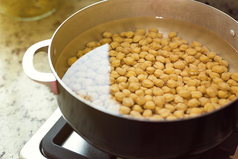 Chick,peas,in,pan,with,water,on,cooker,,cooking,process.
