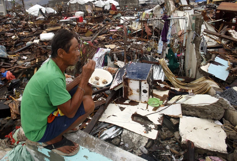אחד הניצולים מהטייפון אוכל ברקע ההרס הרב