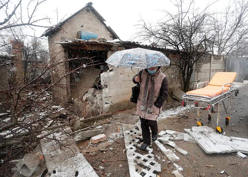 אישה צועדת ליד בית שנפגע בהפגזות על דונייצק שבמזרח אוקראינה