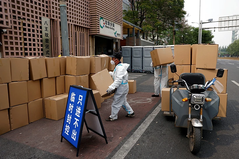 עובד בחליפת מגן מעביר ארגזים מחוץ למתחם מגורים תחת סגר על רקע התפרצות הקורונה בבייג'ינג
