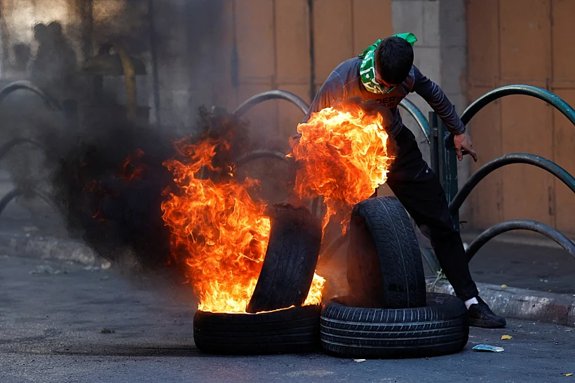 פלסטיני מבעיר צמיגים בחברון