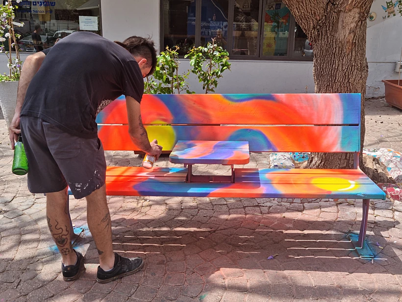אמן אמנות הרחוב MY LUCY מצייר על ספסל בנחלת בנימין. צילום: דינה שגב