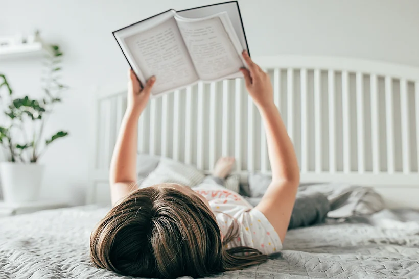 Girl,lies,on,bed,,reading,the,book.,comfort,,cozy,home