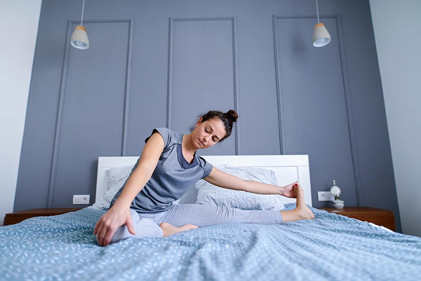 Fit,middle,age,woman,stretching,her,leg,in,her,bed