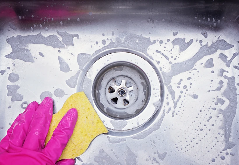Close,up,sink,drain,and,hand,wearing,pink,rubber,glove