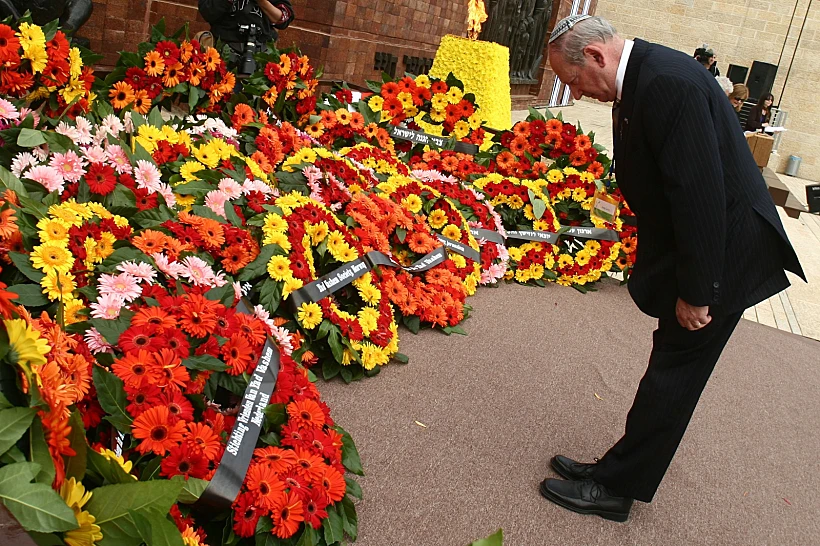 ניצול שואה מניח זר פרחים ביד ושם