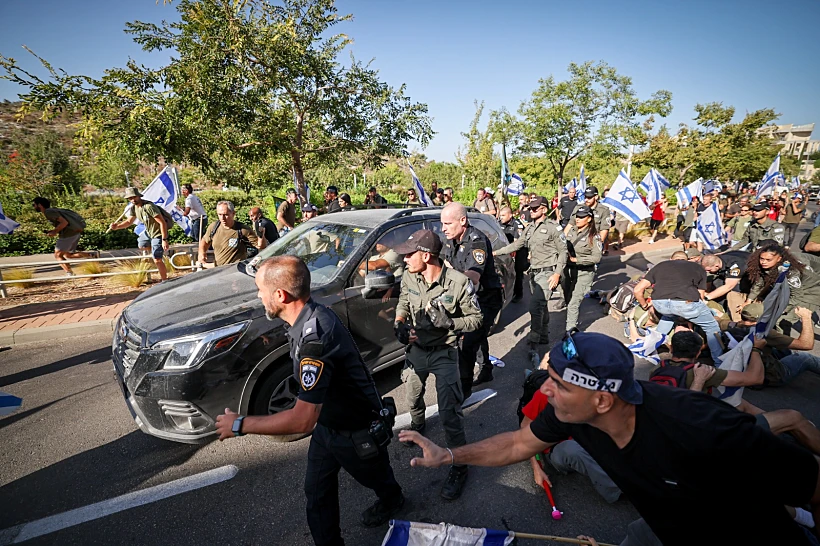 רכבו של לוין נוסע בין המפגינים תחת אבטחה כבדה