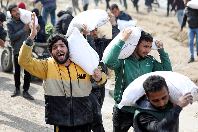 עזתים סוחבים שקי קמח ממשאיות סיוע בעיר עזה
