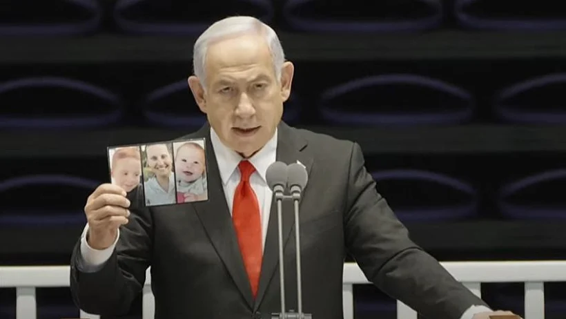 נתניהו מציג את תמונתם של שירי אריאל וכפיר ביבס במהלך נאומו בטקס סיום קורס קצינים