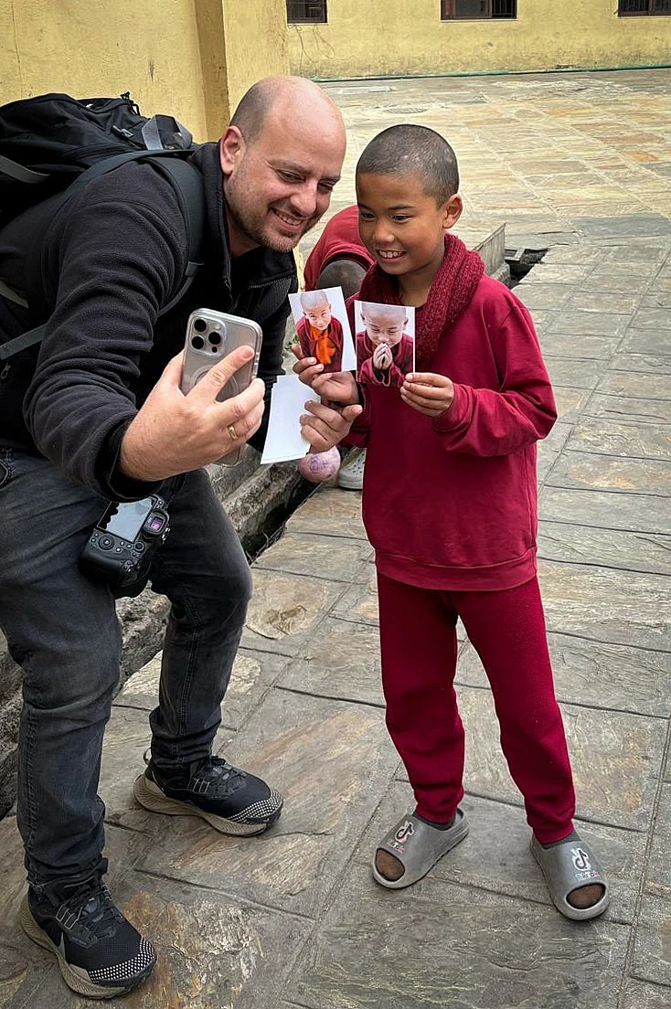 נזיר בודהיסטי צעיר מקבל ממני במתנה תמונות שלו שצילמתי בביקור קודם בקטמנדו.