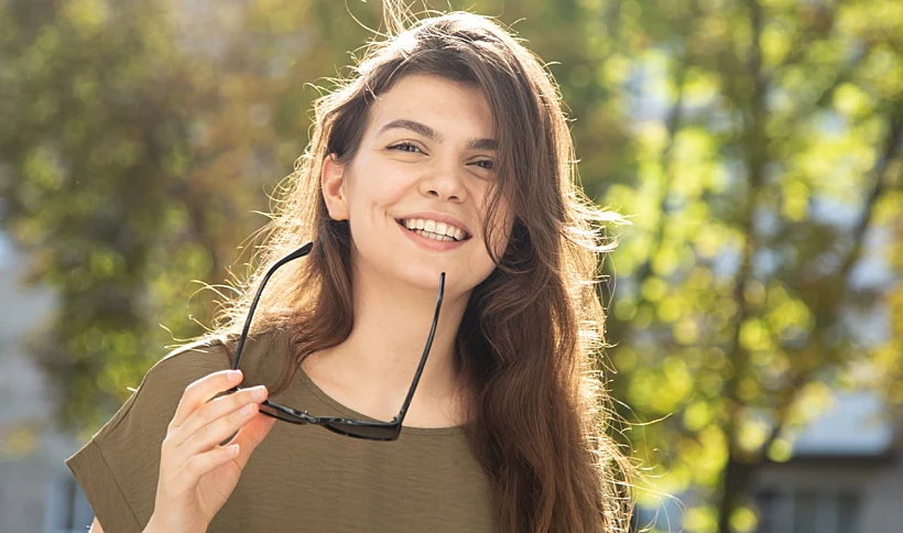 Portrait Of An Attractive Young Woman On A Blurred Background On A Sunny Day.