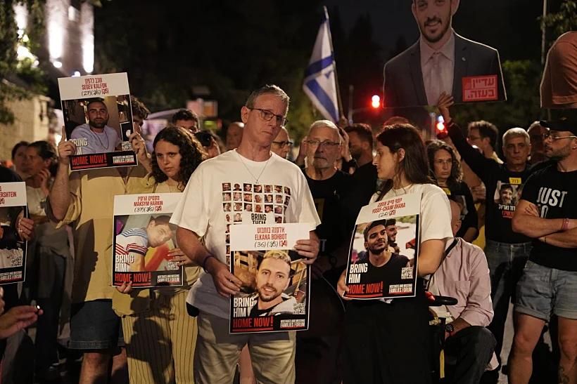 אוהד בן עמי ובנותיו עם תמונותיהם של החטופים שהוחזקו עמו בשבי