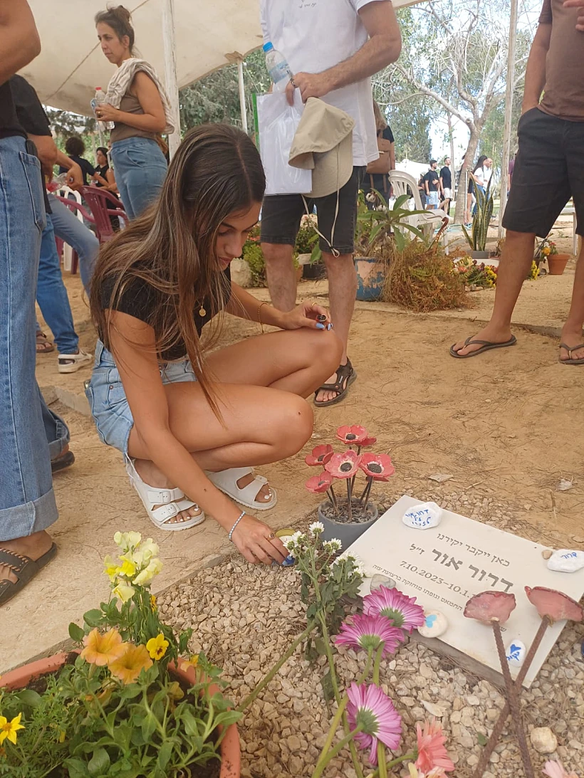 עלמה אור בת ה-15, שנחטפה מקיבוץ בארי ושוחררה אחרי 50 ימים בשבי יחד עם אחיה נעם, מדליקה נר נשמה בחלקת הקבר השמורה לאביה, דרור אור ז"ל, שעדיין חטוף בשבי חמאס