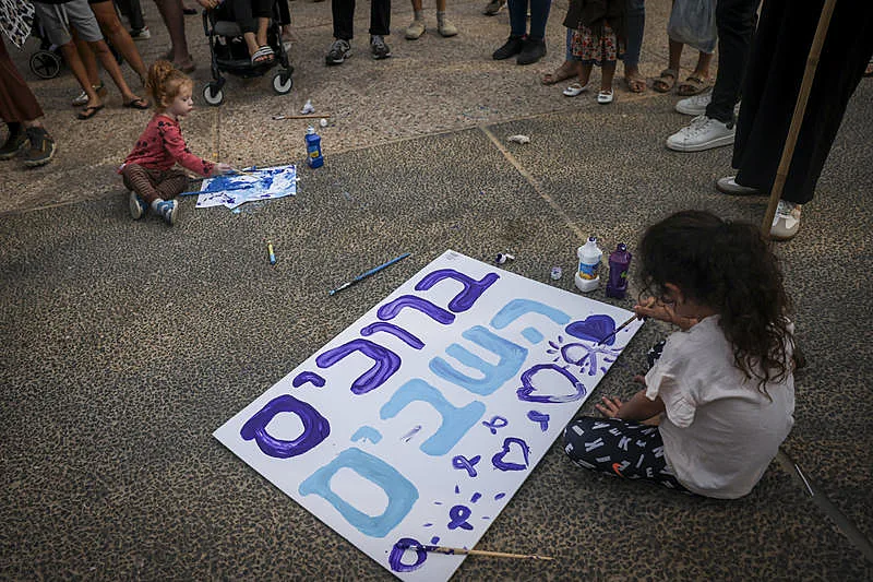 ילדים מכינים שלטים בכיכר החטופים