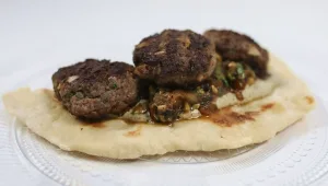 קבב על מצע של טחינה שחורה וסלט משוויאה בליווי לאפה