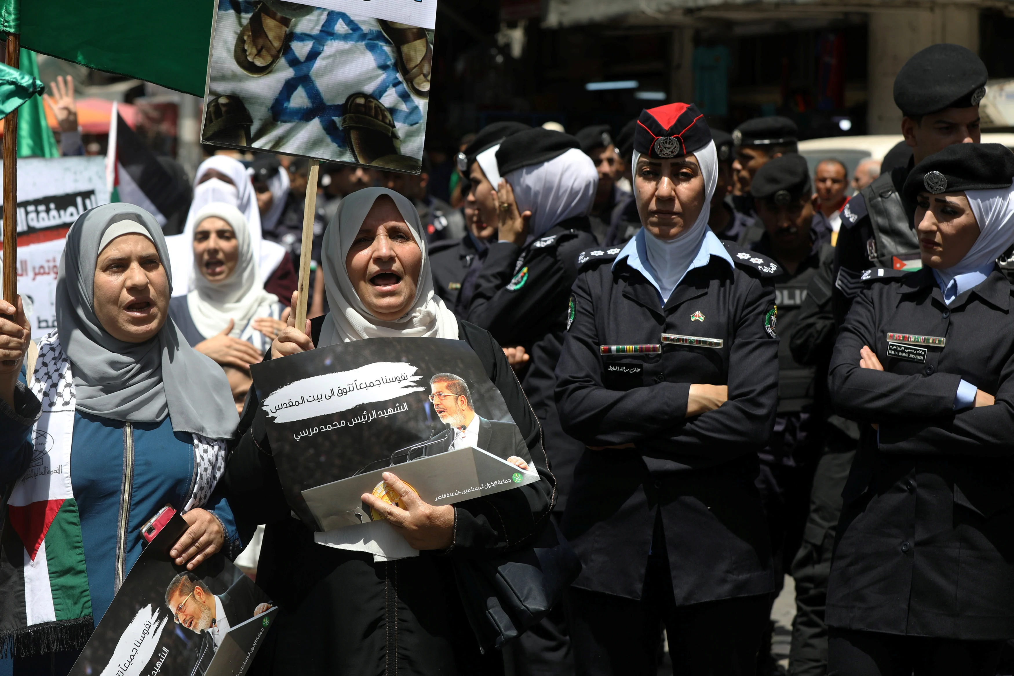Jordanian Police Stand Guard As A Protester Holds A Poster Of Former Egyptian President Mohamed Mursi, As She Chants Slogans During A Protest Against U.s. President In Amman