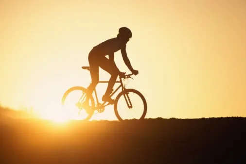 גבר רוכב על אופניים וברקע השקיעה
