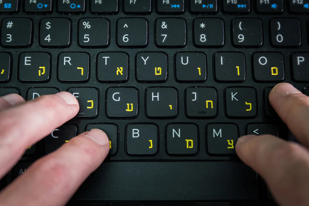 איש מקליד על מקלדת עם אותיות בעברית