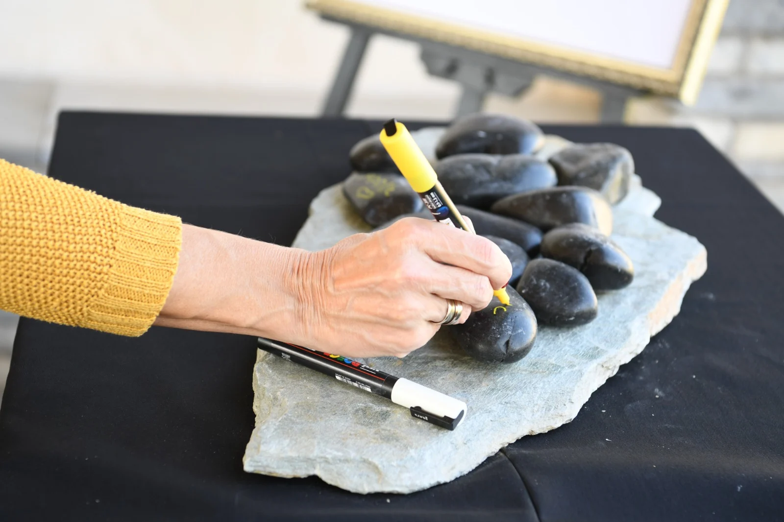 ''על אחד השולחנות מונחים חלוקי נחל, ולצידם טושים עבים, כדי לכתוב מילות פרידה. כל מי שמגיע לטקס מוזמן לכתוב על אבן אם הוא רוצה בכך. בסוף הטקס, האבנים יונחו בקערה יפה ויוגשו למשפחת המנוח''