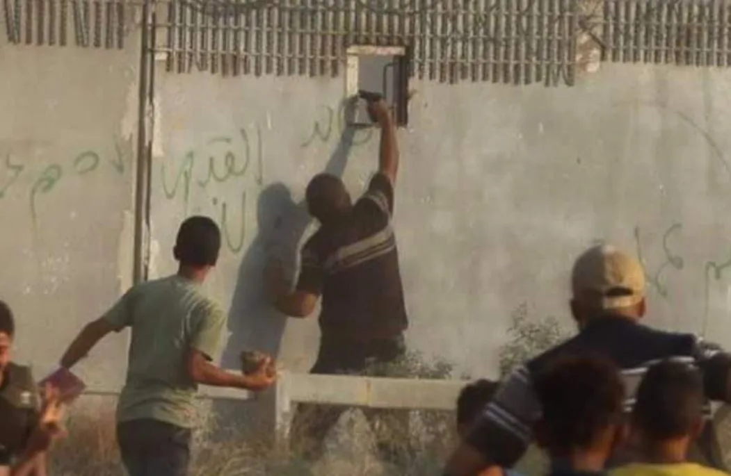 פלסטיני מכוון אקדח ויורה לתוך חרך ירי