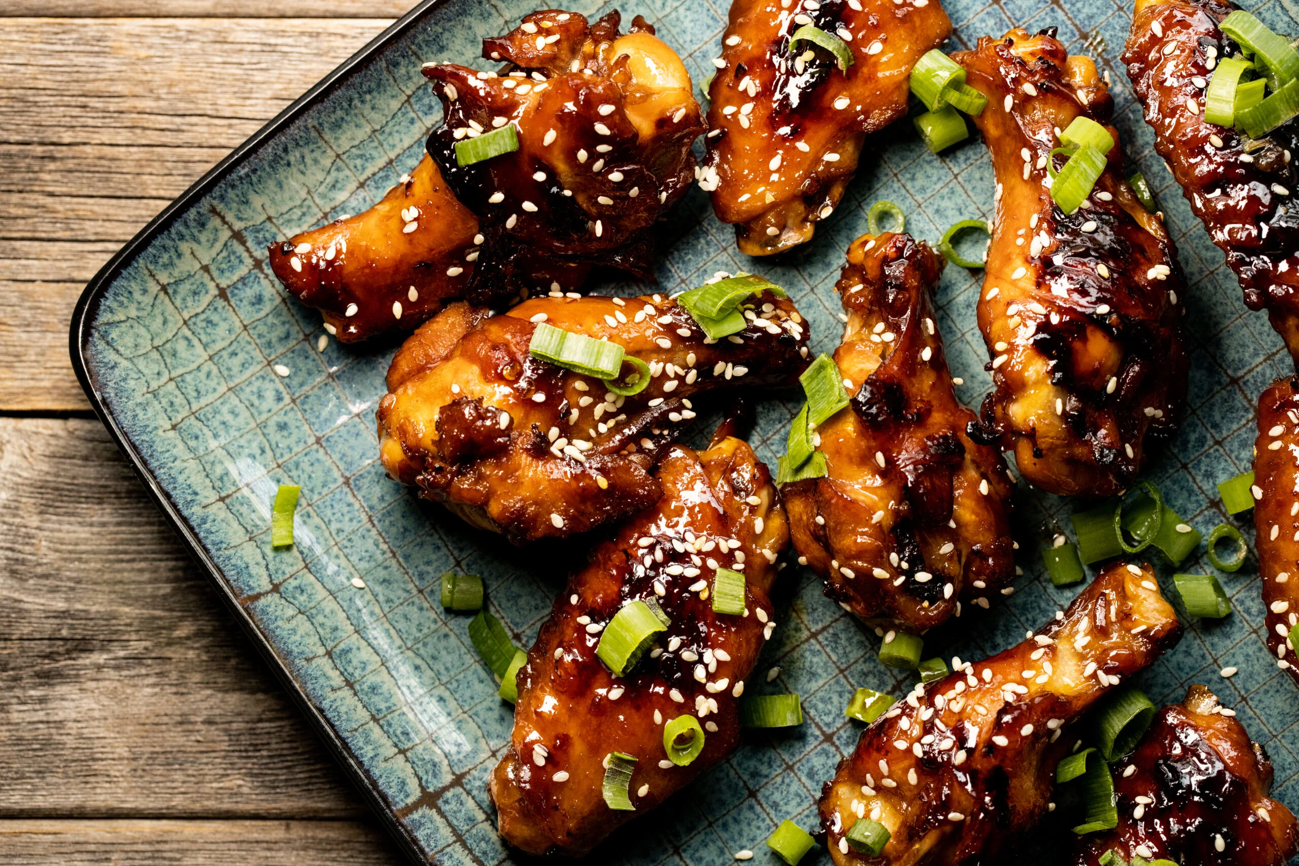 Plate,of,teriyaki,style,chicken,wings,on,rustic,wood,table.