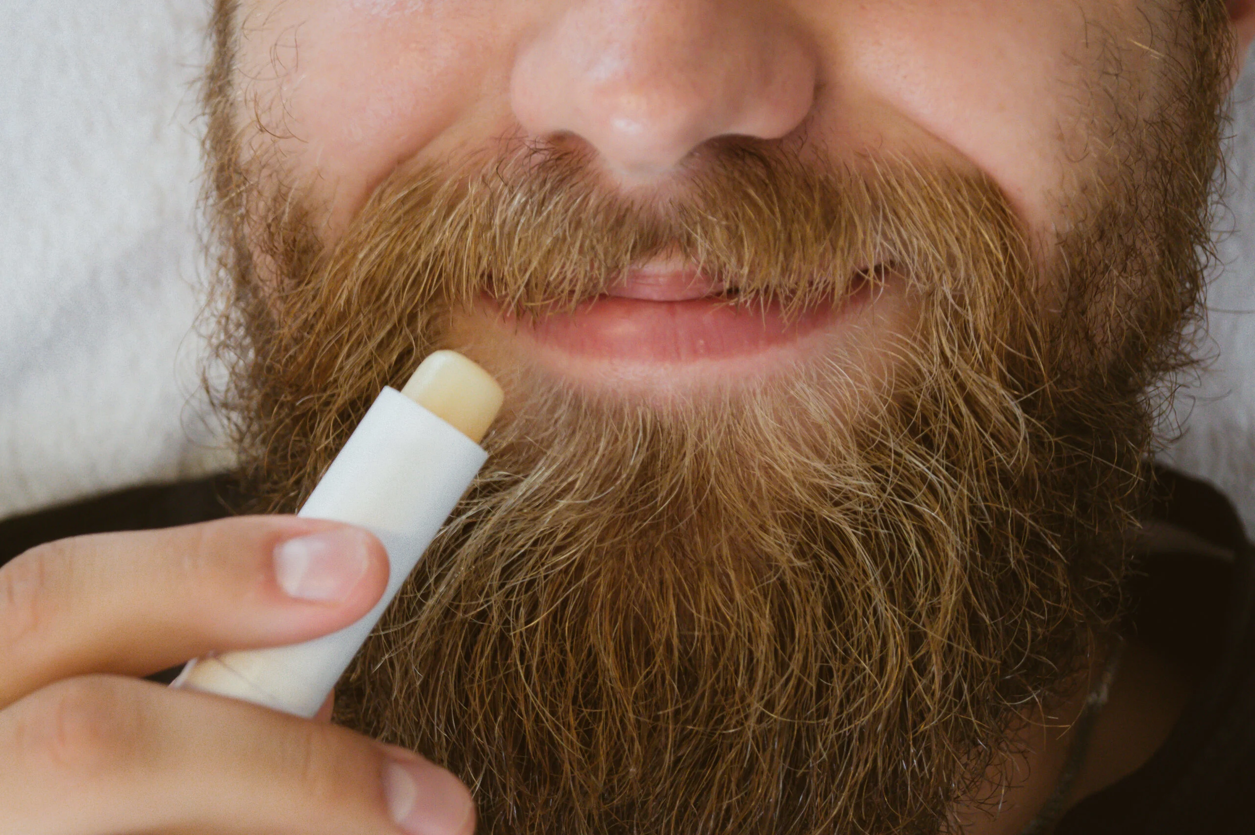Man,applying,lip,balm,in,stick,on,his,lips.,taking
