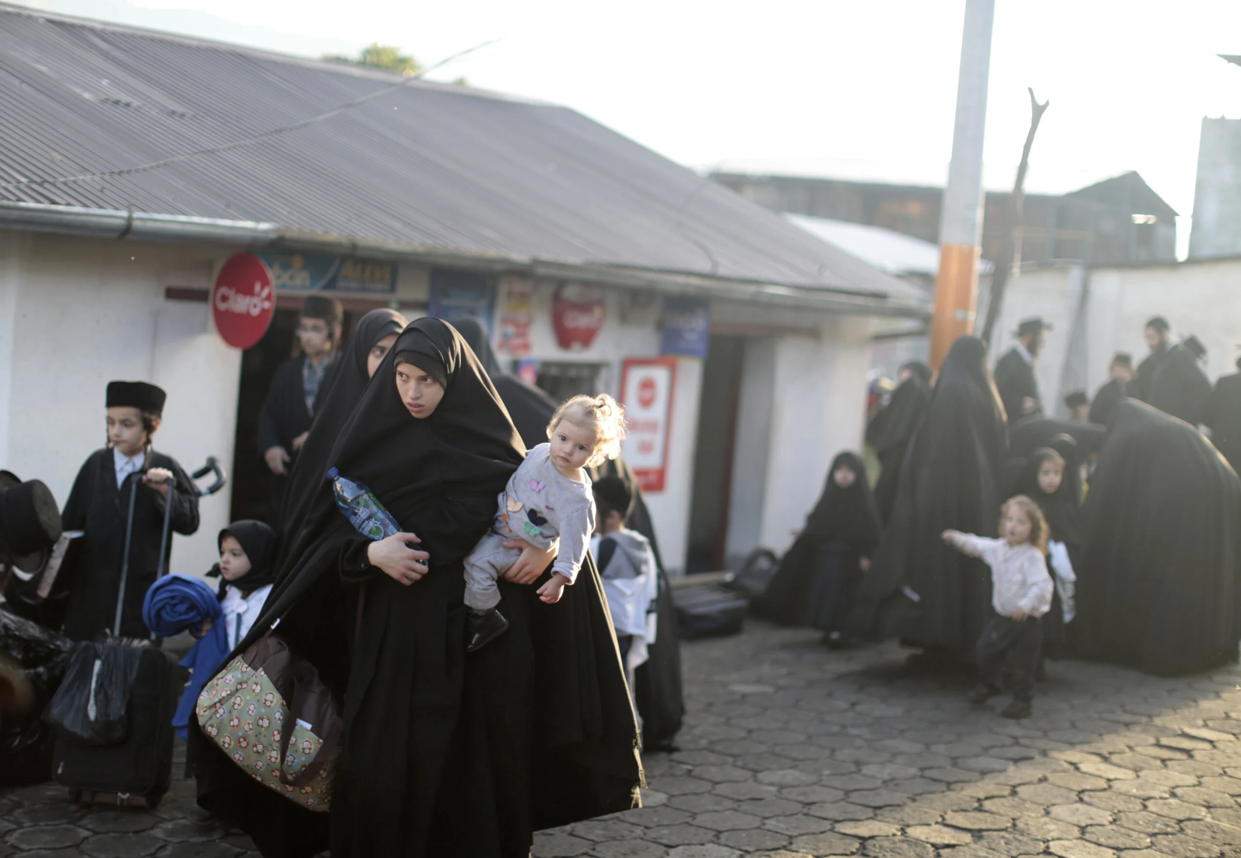 Members Of A Jewish Community Stand With Their Belongings On A Street Before Boarding Buses In San Juan La Laguna