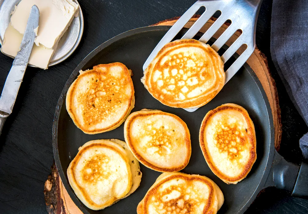Small,pancakes,in,a,pan,on,a,wooden,board.